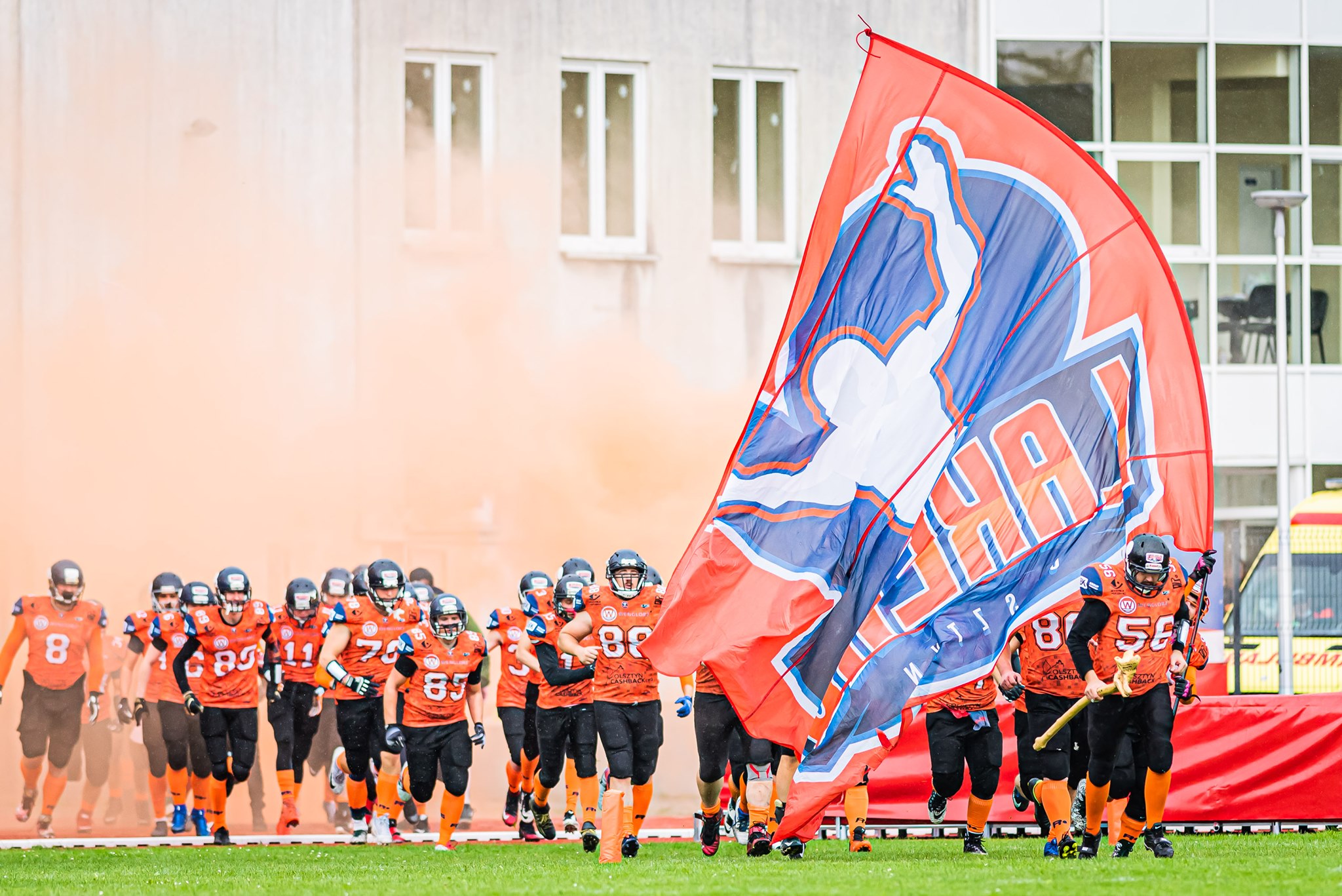 The Olsztyn Lakers team entering the field behind the club flag
